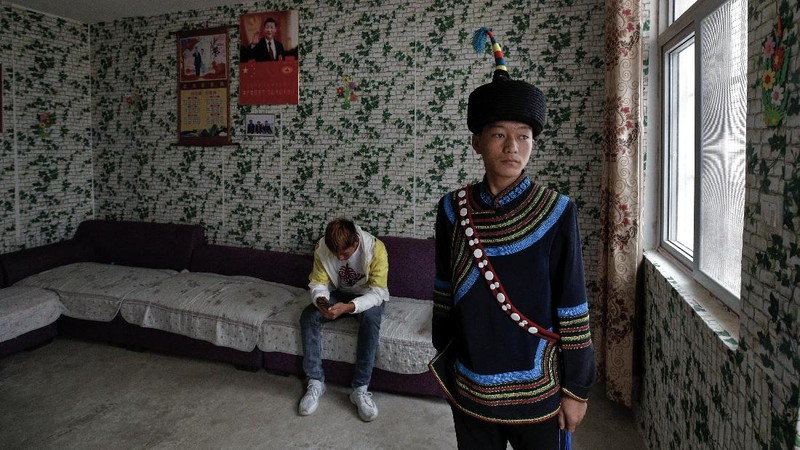 A Yi ethnic minority member stands inside his house displaying posters of Chinese President Xi Jinping and his wife Peng Liyuan, in Xujiashan village in Ganluo County, southwest China's Sichuan province, on Sept. 10, 2020. Communist Party Xi’s smiling visage looks down from the walls of virtually every home inhabited by members of the Yi minority group in a remote corner of China’s Sichuan province. Xi has replaced former leader Mao Zedong for pride of place in new brick and concrete homes built to replace crumbling traditional structures in Sichuan’s Liangshan Yi Autonomous Prefecture, which his home to about 2 million members of the group. (AP Photo/Andy Wong)