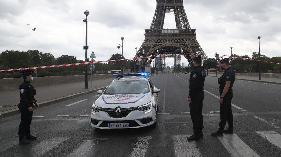 A Russian tourist holding a bottle of Champagne walks past police officers securing the bridge leading to the Eiffel Tower, Wednesday, Sept. 23, 2020 in Paris. Paris police have blockaded the area around the Eiffel Tower after a phone-in bomb threat. (AP Photo/Michel Euler)