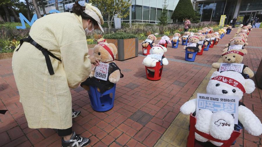 Street vendors sit to protest against a crackdown on illegal street vendors, in front of the Mapo ward office in Seoul, South Korea, Thursday, Sept. 24, 2020. They replaced protestors with teddy bears to avoid the violation of an ongoing ban on rallies with more than 10 people amid the coronavirus pandemic. The signs read: 