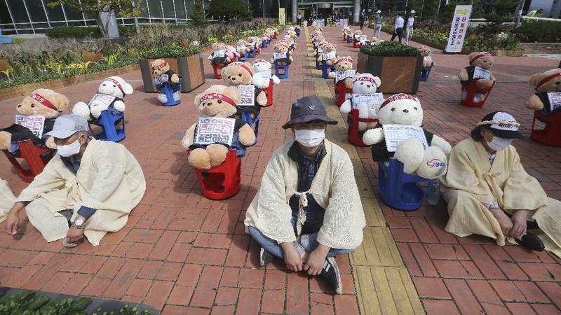 Street vendors sit to protest against a crackdown on illegal street vendors, in front of the Mapo ward office in Seoul, South Korea, Thursday, Sept. 24, 2020. They replaced protestors with teddy bears to avoid the violation of an ongoing ban on rallies with more than 10 people amid the coronavirus pandemic. The signs read: 