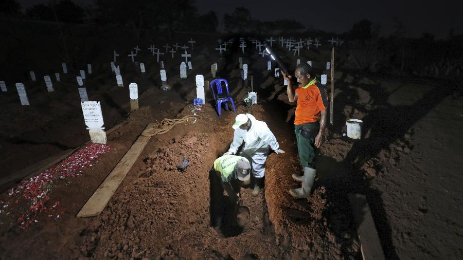 Indonesian Muslim women walk near grave marks at the special section of Pondok Ranggon cemetery which was opened to accommodate the surge in deaths during coronavirus outbreak in Jakarta, Indonesia, Thursday, Sept. 24, 2020. (AP Photo/Dita Alangkara)