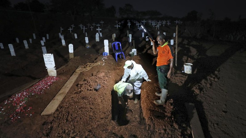 Indonesian Muslim women walk near grave marks at the special section of Pondok Ranggon cemetery which was opened to accommodate the surge in deaths during coronavirus outbreak in Jakarta, Indonesia, Thursday, Sept. 24, 2020. (AP Photo/Dita Alangkara)