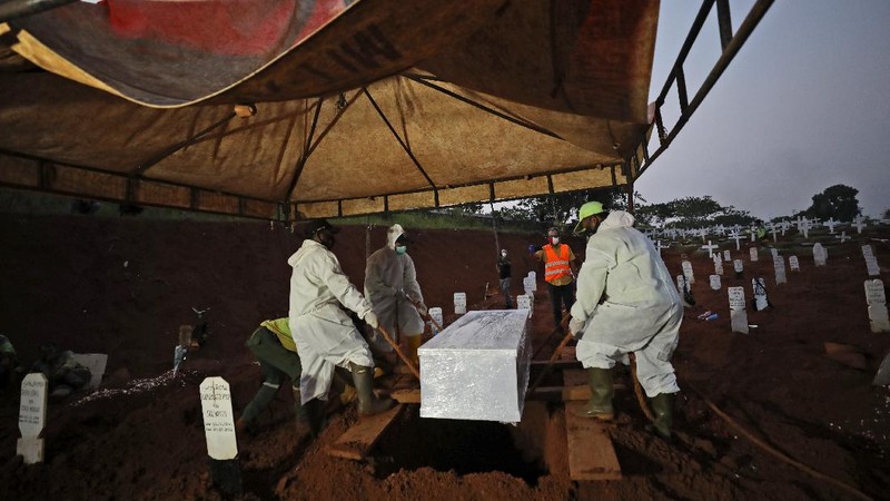 Indonesian Muslim women walk near grave marks at the special section of Pondok Ranggon cemetery which was opened to accommodate the surge in deaths during coronavirus outbreak in Jakarta, Indonesia, Thursday, Sept. 24, 2020. (AP Photo/Dita Alangkara)