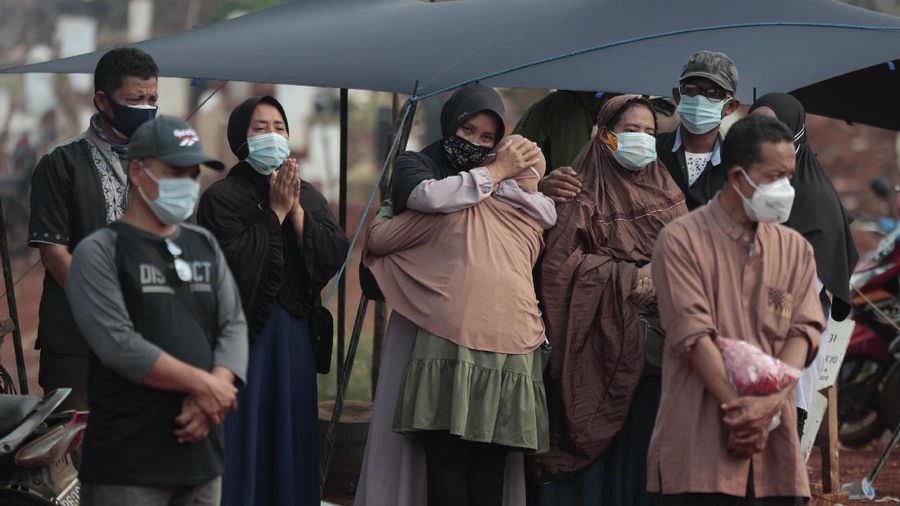 Indonesian Muslim women walk near grave marks at the special section of Pondok Ranggon cemetery which was opened to accommodate the surge in deaths during coronavirus outbreak in Jakarta, Indonesia, Thursday, Sept. 24, 2020. (AP Photo/Dita Alangkara)