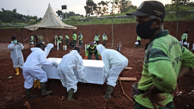 Indonesian Muslim women walk near grave marks at the special section of Pondok Ranggon cemetery which was opened to accommodate the surge in deaths during coronavirus outbreak in Jakarta, Indonesia, Thursday, Sept. 24, 2020. (AP Photo/Dita Alangkara)