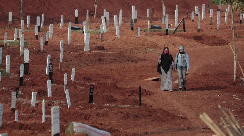 Indonesian Muslim women walk near grave marks at the special section of Pondok Ranggon cemetery which was opened to accommodate the surge in deaths during coronavirus outbreak in Jakarta, Indonesia, Thursday, Sept. 24, 2020. (AP Photo/Dita Alangkara)