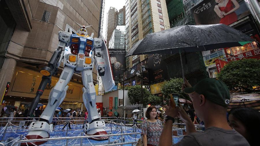 A man takes photos of a 1/3 scale model of the giant robot Gundam, made of steel and fabric glass, displayed during an exhibition in Hong Kong's Times Square Friday, Aug. 2, 2013. The 2-ton (4.409-pound) and 6-meter (19-foot, 7-inch)-tall figure is said to be the largest Gundam ever showcased outside of Japan. (AP Photo/Vincent Yu)