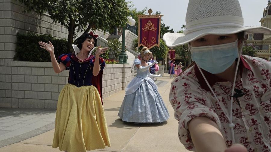 Visitors wearing face masks line up to take photos with the iconic cartoon characters Donald Duck and Daisy Duck at the Hong Kong Disneyland, Friday, Sept. 25, 2020. Hong Kong Disneyland reopened its doors to visitors after closed temporarily due to the coronavirus outbreak. (AP Photo/Kin Cheung)