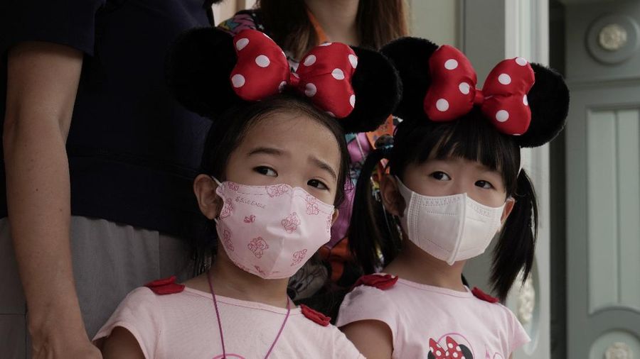 Visitors wearing face masks line up to take photos with the iconic cartoon characters Donald Duck and Daisy Duck at the Hong Kong Disneyland, Friday, Sept. 25, 2020. Hong Kong Disneyland reopened its doors to visitors after closed temporarily due to the coronavirus outbreak. (AP Photo/Kin Cheung)