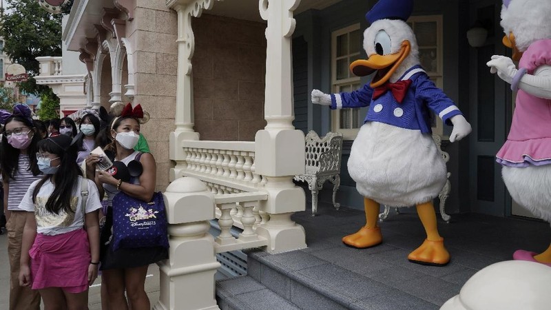 Visitors wearing face masks line up to take photos with the iconic cartoon characters Donald Duck and Daisy Duck at the Hong Kong Disneyland, Friday, Sept. 25, 2020. Hong Kong Disneyland reopened its doors to visitors after closed temporarily due to the coronavirus outbreak. (AP Photo/Kin Cheung)