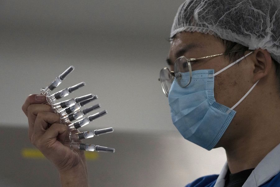 A worker inspects vials of SARS CoV-2 Vaccine for COVID-19 produced by SinoVac at its factory in Beijing on Thursday, Sept. 24, 2020. A Chinese health official said Friday, Sept. 25, 2020, that the country's annual production capacity for coronavirus vaccines will top 1 billion doses next year, following an aggressive government support program for construction of new factories. (AP Photo/Ng Han Guan)