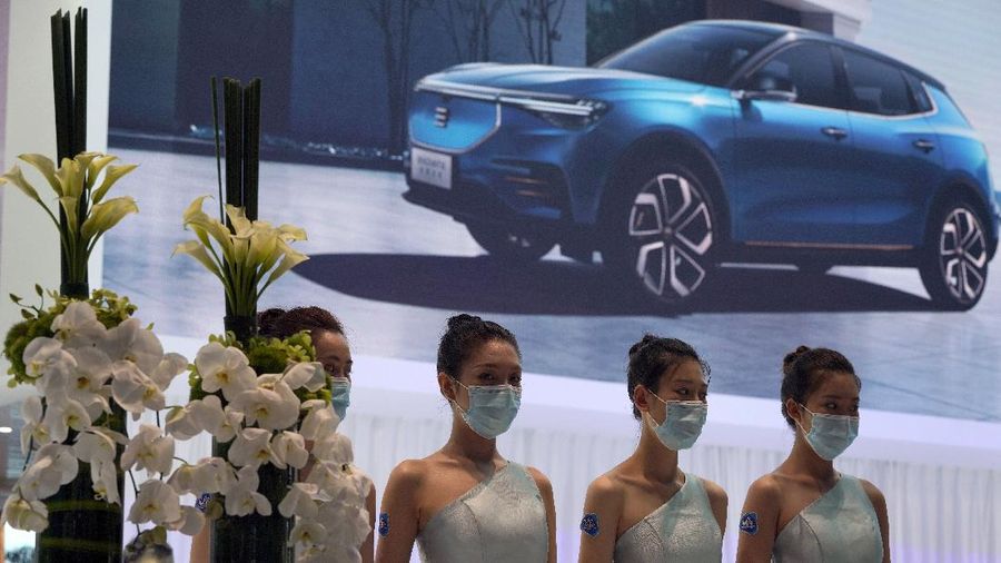 Receptionists with Chinese automaker Enovate waits for attendees of the Auto China 2020 show in Beijing on Saturday, Sept. 26, 2020. Ford, Nissan and BMW unveiled electric models with more range for China on Saturday as the Beijing auto show opened under anti-virus controls that included holding news conferences by international video link.(AP Photo/Ng Han Guan)