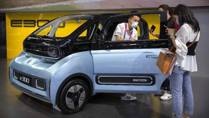 Receptionists with Chinese automaker Enovate waits for attendees of the Auto China 2020 show in Beijing on Saturday, Sept. 26, 2020. Ford, Nissan and BMW unveiled electric models with more range for China on Saturday as the Beijing auto show opened under anti-virus controls that included holding news conferences by international video link.(AP Photo/Ng Han Guan)