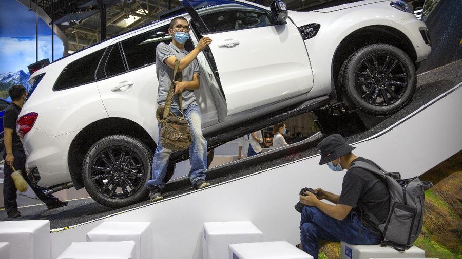 A visitor wearing a face mask to protect against the coronavirus looks at a Ford Everest Titanium Sport vehicle on display at the Beijing International Automotive Exhibition, also known as Auto China, in Beijing, Saturday, Sept. 26, 2020. Auto China 2020, postponed from March, is the first major trade show for any industry since the pandemic began as automakers are looking to China, the first major economy to start recovering from the coronavirus pandemic, to drive sales growth and reverse multibillion-dollar losses. (AP Photo/Mark Schiefelbein)