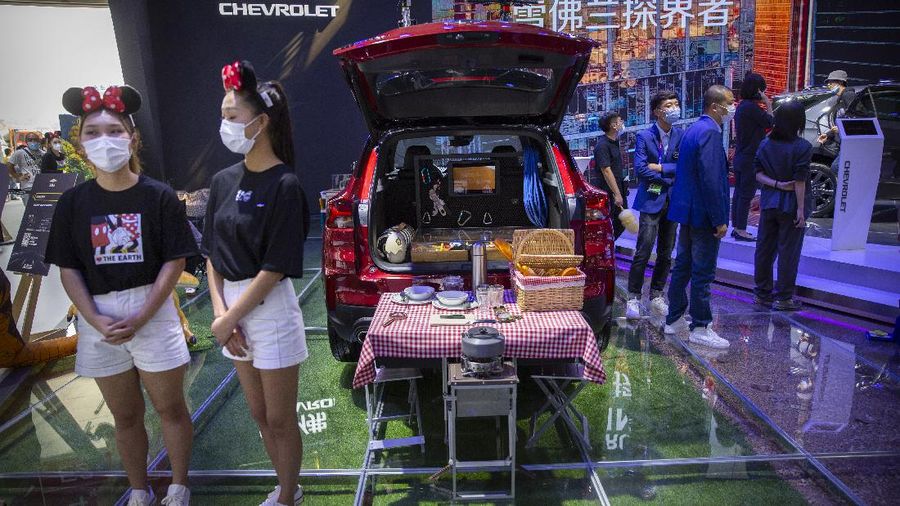 Receptionists with Chinese automaker Enovate waits for attendees of the Auto China 2020 show in Beijing on Saturday, Sept. 26, 2020. Ford, Nissan and BMW unveiled electric models with more range for China on Saturday as the Beijing auto show opened under anti-virus controls that included holding news conferences by international video link.(AP Photo/Ng Han Guan)