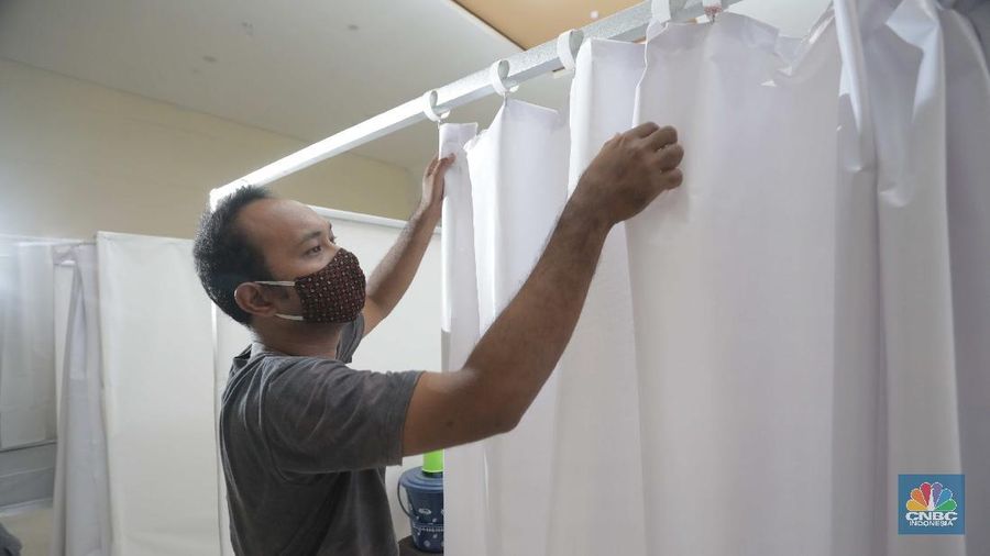 Petugas melintasi ruang isolasi mandiri pasien COVID-19 di Gelanggang Remaja Kecamatan Pademangan, Jakarta, Senin (28/9/2020). Sebanyak 30 bilik isolasi pasien Covid-19 disediakan dengan fasilitas tempat tidur, lemari, dan peralatan mandi. Gelanggang ini juga menjadi tempat percontohan graha sehat mandiri pasien Covid-19 di DKI berdasarkan kajian dari dewan riset DKI Jakarta. Meski belum diketahui pasti kapan Gelanggang Remaja Kecamatan Pademangan digunakan, prinsipnya Dispora DKI Jakarta menyiapkan fasilitas olahraga seperti Gelanggang Remaja dan GOR lainnya sebagai alternatif tempat untuk isolasi mandiri. (CNBC Indonesia/ Muhammad Sabki)