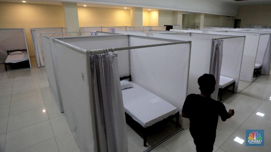 Petugas melintasi ruang isolasi mandiri pasien COVID-19 di Gelanggang Remaja Kecamatan Pademangan, Jakarta, Senin (28/9/2020). Sebanyak 30 bilik isolasi pasien Covid-19 disediakan dengan fasilitas tempat tidur, lemari, dan peralatan mandi. Gelanggang ini juga menjadi tempat percontohan graha sehat mandiri pasien Covid-19 di DKI berdasarkan kajian dari dewan riset DKI Jakarta. Meski belum diketahui pasti kapan Gelanggang Remaja Kecamatan Pademangan digunakan, prinsipnya Dispora DKI Jakarta menyiapkan fasilitas olahraga seperti Gelanggang Remaja dan GOR lainnya sebagai alternatif tempat untuk isolasi mandiri. (CNBC Indonesia/ Muhammad Sabki)