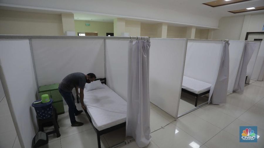 Petugas melintasi ruang isolasi mandiri pasien COVID-19 di Gelanggang Remaja Kecamatan Pademangan, Jakarta, Senin (28/9/2020). Sebanyak 30 bilik isolasi pasien Covid-19 disediakan dengan fasilitas tempat tidur, lemari, dan peralatan mandi. Gelanggang ini juga menjadi tempat percontohan graha sehat mandiri pasien Covid-19 di DKI berdasarkan kajian dari dewan riset DKI Jakarta. Meski belum diketahui pasti kapan Gelanggang Remaja Kecamatan Pademangan digunakan, prinsipnya Dispora DKI Jakarta menyiapkan fasilitas olahraga seperti Gelanggang Remaja dan GOR lainnya sebagai alternatif tempat untuk isolasi mandiri. (CNBC Indonesia/ Muhammad Sabki)
