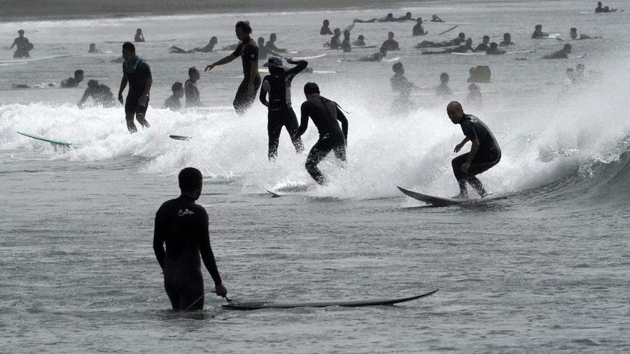 People surf at windy Katase-kaigan beach in Fujisawa, Kanagawa prefecture, south of Tokyo Thursday, Sept. 24, 2020. Tropical Storm Dolphin moved along Japan's Pacific coast. (AP Photo/Eugene Hoshiko)