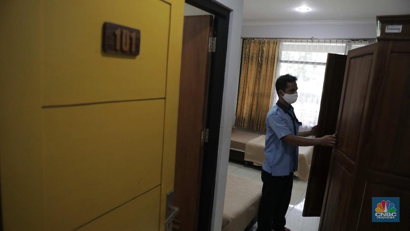 Petugas merapikan kamar yang disiapkan untuk isolasi Covid-19 di Graha Wisata Ragunan, Rabu (30/9). Graha Wisata Ragunan menjadi salah satu lokasi yang ditetapkan menjadi tempat isolasi pasien COVID-19 oleh. 152 kamar tersedia di tempat ini. Gedung yang berlokasi di Jalan Harsono RM, Ragunan, Pasar Minggu, Jakarta Selatan (Jaksel) itu memiliki 3 lantai. Di depan setiap kamar, tampak ada 1 meja. Sejumlah kamar diisi 2 tempat tidur, namun ada juga kamar yang memiliki 6 tempat tidur. Untuk kamar yang ditaruh 2 tempat tidur, diberi jarak sekitar 1,5 hingga 2 meter. (CNBC Indonesia/ Muhammad Sabki)