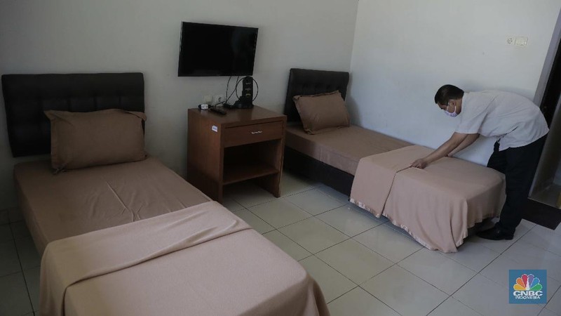 Petugas merapikan kamar yang disiapkan untuk isolasi Covid-19 di Graha Wisata Ragunan, Rabu (30/9). Graha Wisata Ragunan menjadi salah satu lokasi yang ditetapkan menjadi tempat isolasi pasien COVID-19 oleh. 152 kamar tersedia di tempat ini. Gedung yang berlokasi di Jalan Harsono RM, Ragunan, Pasar Minggu, Jakarta Selatan (Jaksel) itu memiliki 3 lantai. Di depan setiap kamar, tampak ada 1 meja. Sejumlah kamar diisi 2 tempat tidur, namun ada juga kamar yang memiliki 6 tempat tidur. Untuk kamar yang ditaruh 2 tempat tidur, diberi jarak sekitar 1,5 hingga 2 meter. (CNBC Indonesia/ Muhammad Sabki)