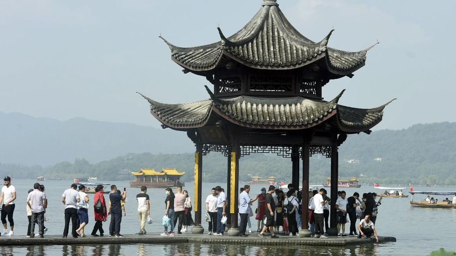 Tourists gather at a waterfront pavilion at the West Lake in Hangzhou in eastern China's Zhejiang Province, Thursday, Oct. 1, 2020. Millions of Chinese tourists usually would use their week-long National Day holidays to travel abroad. This year, travel restrictions due to the coronavirus pandemic mean that some 600 million tourists - about 40% of the population - will travel within China during the holiday that began Thursday, according to Ctrip, China's largest online travel agency. (Chinatopix via AP)