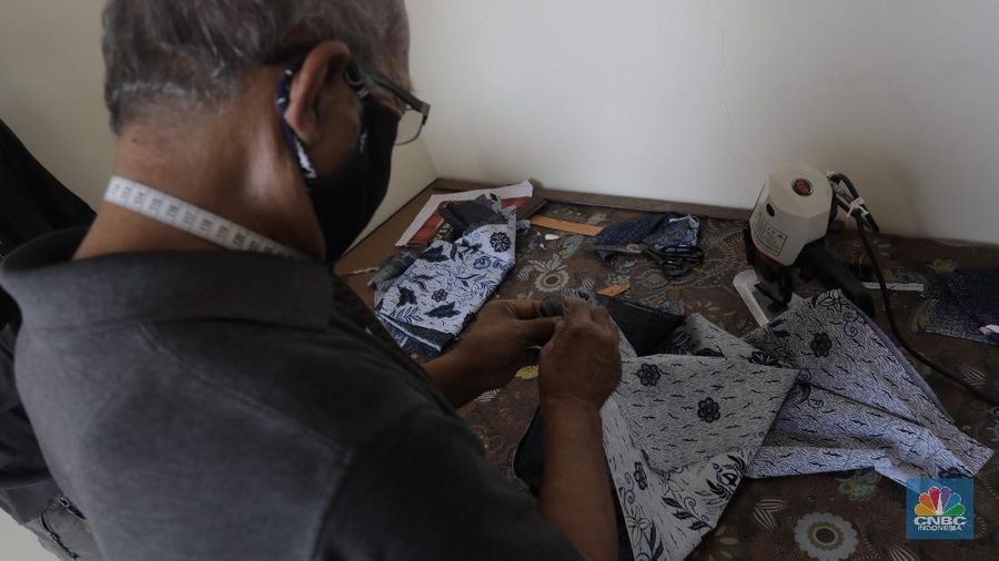 Perajin memproduksi masker batik di Sentra Kerajinan Batik Tradisiku, Kota Bogor, Jawa Barat, Jumat (2/10/2020). Pemerintah tanggal 2 Oktober sebagai Hari Batik Nasional. Penetapan tersebut berlandaskan keputusan Perserikatan Bangsa-Bangsa (PBB) yang menetapkan batik menjadi warisan budaya dunia dari Indonesia. Galeri Batik ini merupakan salah satu pusat di mana pengunjung dapat melihat dan memesan batik yang desainnya amat kental dengan nuansa Kota Bogor. Biasanya wisatawan yang hadir ke Bogor bisa melihat dan mengunjungi Galeri Batik ini. Karena adanya aturan PSBB membuat turis asing tidak bisa datang. Ragam desainnya pun rupa-rupa mulai dari motif hujan gerimis, kujang, Kebun Raya, Istana Bogor, dan Batu Tulis. Untuk saat ini perajin sedang garap masker dengan motif batik standar SNI. Seperti diketahui Badan Standardisasi Nasional (BSN) mengeluarkan spesifikasi masker kain ber-SNI yang terbagi menjadi tiga tipe berdasarkan penggunaannya, antara lain tipe A untuk penggunaan umum, tipe B untuk penggunaan filtrasi bakteri, dan tipe C untuk penggunaan filtrasi partikel. (CNBC Indonesia/ Muhammad Sabki
