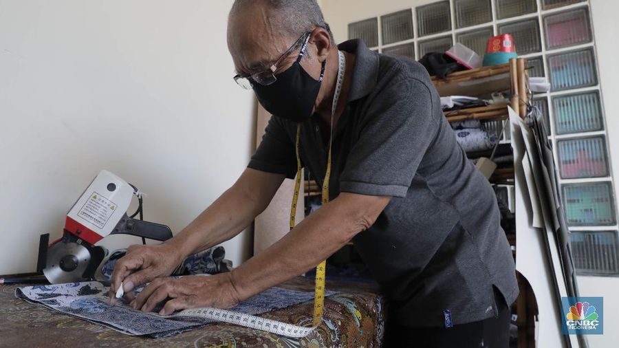 Perajin memproduksi masker batik di Sentra Kerajinan Batik Tradisiku, Kota Bogor, Jawa Barat, Jumat (2/10/2020). Pemerintah tanggal 2 Oktober sebagai Hari Batik Nasional. Penetapan tersebut berlandaskan keputusan Perserikatan Bangsa-Bangsa (PBB) yang menetapkan batik menjadi warisan budaya dunia dari Indonesia. Galeri Batik ini merupakan salah satu pusat di mana pengunjung dapat melihat dan memesan batik yang desainnya amat kental dengan nuansa Kota Bogor. Biasanya wisatawan yang hadir ke Bogor bisa melihat dan mengunjungi Galeri Batik ini. Karena adanya aturan PSBB  membuat turis asing tidak bisa datang. Ragam desainnya pun rupa-rupa mulai dari motif hujan gerimis, kujang, Kebun Raya, Istana Bogor, dan Batu Tulis. Untuk saat ini perajin sedang garap masker dengan motif batik standar SNI. Seperti diketahui Badan Standardisasi Nasional (BSN) mengeluarkan spesifikasi masker kain ber-SNI yang terbagi menjadi tiga tipe berdasarkan penggunaannya, antara lain tipe A untuk penggunaan umum, tipe B untuk penggunaan filtrasi bakteri, dan tipe C untuk penggunaan filtrasi partikel. (CNBC Indonesia/ Muhammad Sabki