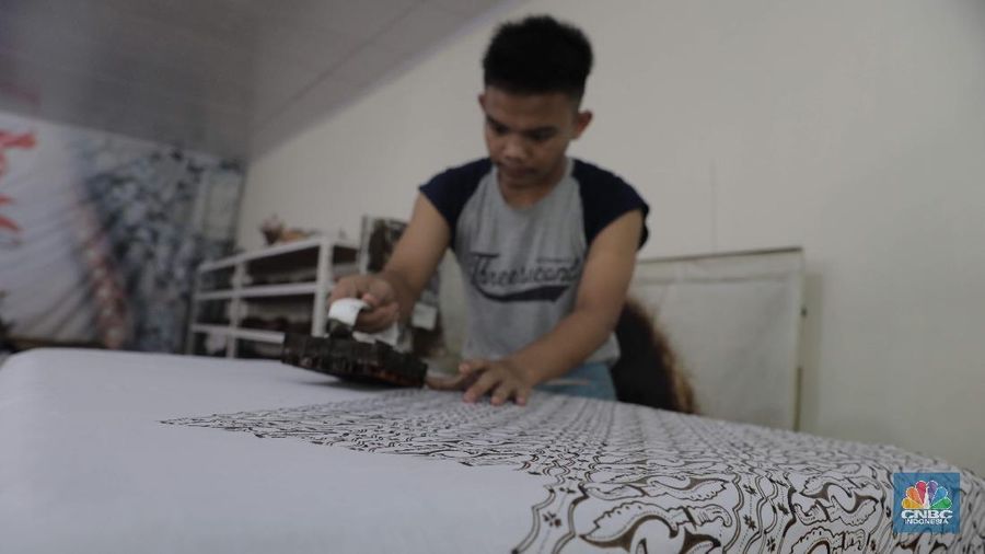 Perajin memproduksi masker batik di Sentra Kerajinan Batik Tradisiku, Kota Bogor, Jawa Barat, Jumat (2/10/2020). Pemerintah tanggal 2 Oktober sebagai Hari Batik Nasional. Penetapan tersebut berlandaskan keputusan Perserikatan Bangsa-Bangsa (PBB) yang menetapkan batik menjadi warisan budaya dunia dari Indonesia. Galeri Batik ini merupakan salah satu pusat di mana pengunjung dapat melihat dan memesan batik yang desainnya amat kental dengan nuansa Kota Bogor. Biasanya wisatawan yang hadir ke Bogor bisa melihat dan mengunjungi Galeri Batik ini. Karena adanya aturan PSBB  membuat turis asing tidak bisa datang. Ragam desainnya pun rupa-rupa mulai dari motif hujan gerimis, kujang, Kebun Raya, Istana Bogor, dan Batu Tulis. Untuk saat ini perajin sedang garap masker dengan motif batik standar SNI. Seperti diketahui Badan Standardisasi Nasional (BSN) mengeluarkan spesifikasi masker kain ber-SNI yang terbagi menjadi tiga tipe berdasarkan penggunaannya, antara lain tipe A untuk penggunaan umum, tipe B untuk penggunaan filtrasi bakteri, dan tipe C untuk penggunaan filtrasi partikel. (CNBC Indonesia/ Muhammad Sabki