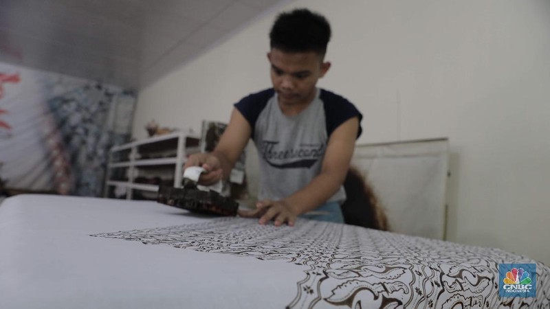 Perajin memproduksi masker batik di Sentra Kerajinan Batik Tradisiku, Kota Bogor, Jawa Barat, Jumat (2/10/2020). Pemerintah tanggal 2 Oktober sebagai Hari Batik Nasional. Penetapan tersebut berlandaskan keputusan Perserikatan Bangsa-Bangsa (PBB) yang menetapkan batik menjadi warisan budaya dunia dari Indonesia. Galeri Batik ini merupakan salah satu pusat di mana pengunjung dapat melihat dan memesan batik yang desainnya amat kental dengan nuansa Kota Bogor. Biasanya wisatawan yang hadir ke Bogor bisa melihat dan mengunjungi Galeri Batik ini. Karena adanya aturan PSBB  membuat turis asing tidak bisa datang. Ragam desainnya pun rupa-rupa mulai dari motif hujan gerimis, kujang, Kebun Raya, Istana Bogor, dan Batu Tulis. Untuk saat ini perajin sedang garap masker dengan motif batik standar SNI. Seperti diketahui Badan Standardisasi Nasional (BSN) mengeluarkan spesifikasi masker kain ber-SNI yang terbagi menjadi tiga tipe berdasarkan penggunaannya, antara lain tipe A untuk penggunaan umum, tipe B untuk penggunaan filtrasi bakteri, dan tipe C untuk penggunaan filtrasi partikel. (CNBC Indonesia/ Muhammad Sabki