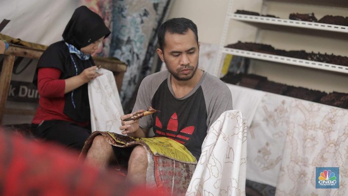 Perajin memproduksi masker batik di Sentra Kerajinan Batik Tradisiku, Kota Bogor, Jawa Barat, Jumat (2/10/2020). Pemerintah tanggal 2 Oktober sebagai Hari Batik Nasional. Penetapan tersebut berlandaskan keputusan Perserikatan Bangsa-Bangsa (PBB) yang menetapkan batik menjadi warisan budaya dunia dari Indonesia. Galeri Batik ini merupakan salah satu pusat di mana pengunjung dapat melihat dan memesan batik yang desainnya amat kental dengan nuansa Kota Bogor. Biasanya wisatawan yang hadir ke Bogor bisa melihat dan mengunjungi Galeri Batik ini. Karena adanya aturan PSBB  membuat turis asing tidak bisa datang. Ragam desainnya pun rupa-rupa mulai dari motif hujan gerimis, kujang, Kebun Raya, Istana Bogor, dan Batu Tulis. Untuk saat ini perajin sedang garap masker dengan motif batik standar SNI. Seperti diketahui Badan Standardisasi Nasional (BSN) mengeluarkan spesifikasi masker kain ber-SNI yang terbagi menjadi tiga tipe berdasarkan penggunaannya, antara lain tipe A untuk penggunaan umum, tipe B untuk penggunaan filtrasi bakteri, dan tipe C untuk penggunaan filtrasi partikel. (CNBC Indonesia/ Muhammad Sabki