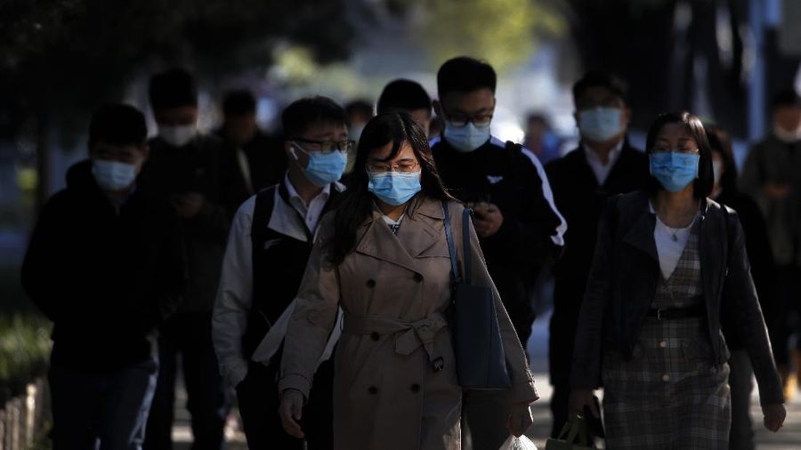 People wearing face masks to help curb the spread of the coronavirus walk on a street during the morning rush hour in Beijing, Monday, Oct. 12, 2020. Even as China has largely controlled the outbreak, the coronavirus is still surging across the globe with ever rising death toll. (AP Photo/Andy Wong)