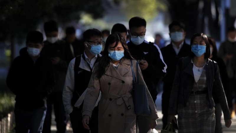 A medical staff takes a swab from a woman as residents line up for the COVID-19 test near the residential area in Qingdao in east China's Shandong province, Monday, Oct. 12, 2020. China's government says all 9 million people in the eastern city of Qingdao will be tested for the coronavirus this week after nine cases linked to a hospital were found. The announcement Monday broke a string of weeks without any locally transmitted infections reported in China. (Chinatopix via AP)