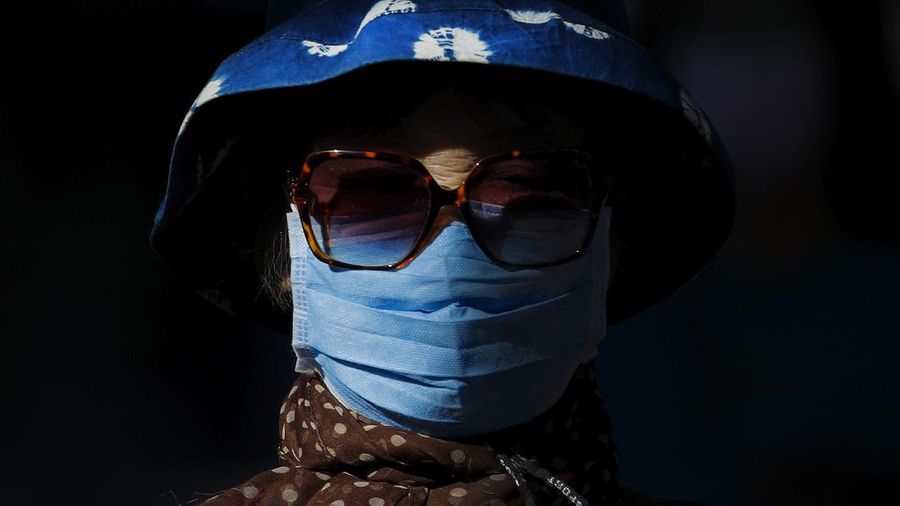 A beam of sunlight is cast on a woman wearing a face mask to help curb the spread of the coronavirus as she walks on a street in Beijing, Monday, Oct. 12, 2020. Even as China has largely controlled the outbreak, the coronavirus is still surging across the globe with ever rising death toll. (AP Photo/Andy Wong)