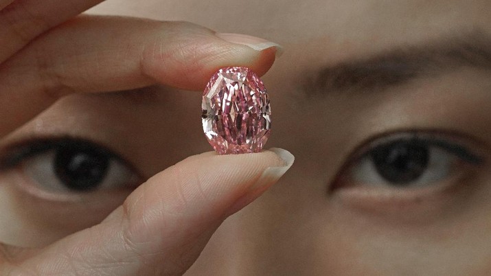 A model displays an ultra-rare 14.83-carat diamond that is one of the largest internally flawless fancy vivid purple-pink gem ever graded by the Gemological Institute of America at a Sotheby's auction room in Hong Kong Monday, Oct. 12, 2020. The diamond will be offered for sale in Geneva on Nov. 11, 2020. (AP Photo/Vincent Yu)