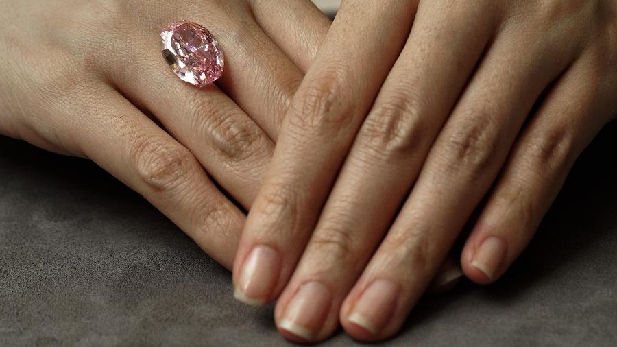 A model displays an ultra-rare 14.83-carat diamond that is one of the largest internally flawless fancy vivid purple-pink gem ever graded by the Gemological Institute of America at a Sotheby's auction room in Hong Kong Monday, Oct. 12, 2020. The diamond will be offered for sale in Geneva on Nov. 11, 2020. (AP Photo/Vincent Yu)