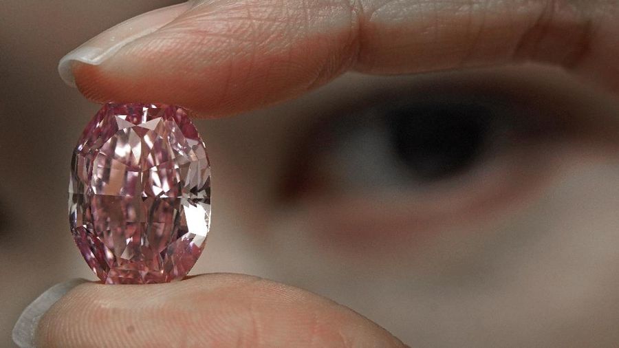 A model displays an ultra-rare 14.83-carat diamond that is one of the largest internally flawless fancy vivid purple-pink gem ever graded by the Gemological Institute of America at a Sotheby's auction room in Hong Kong Monday, Oct. 12, 2020. The diamond will be offered for sale in Geneva on Nov. 11, 2020. (AP Photo/Vincent Yu)