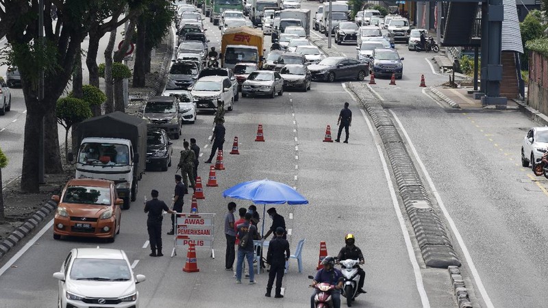 Police officers check vehicles at roadblock to ensure that people abide by the movement control order on the outskirts of Kuala Lumpur, Malaysia, Wednesday, Oct. 14, 2020. Malaysia will restrict movements in its biggest city Kuala Lumpur, neighboring Selangor state and the administrative capital of Putrajaya from Wednesday to curb a sharp rise in coronavirus cases. (AP Photo/Vincent Thian)