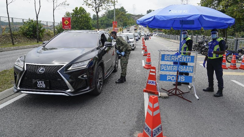 Police officers check vehicles at roadblock to ensure that people abide by the movement control order on the outskirts of Kuala Lumpur, Malaysia, Wednesday, Oct. 14, 2020. Malaysia will restrict movements in its biggest city Kuala Lumpur, neighboring Selangor state and the administrative capital of Putrajaya from Wednesday to curb a sharp rise in coronavirus cases. (AP Photo/Vincent Thian)