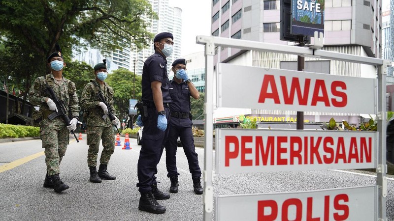 Police officers check vehicles at roadblock to ensure that people abide by the movement control order on the outskirts of Kuala Lumpur, Malaysia, Wednesday, Oct. 14, 2020. Malaysia will restrict movements in its biggest city Kuala Lumpur, neighboring Selangor state and the administrative capital of Putrajaya from Wednesday to curb a sharp rise in coronavirus cases. (AP Photo/Vincent Thian)