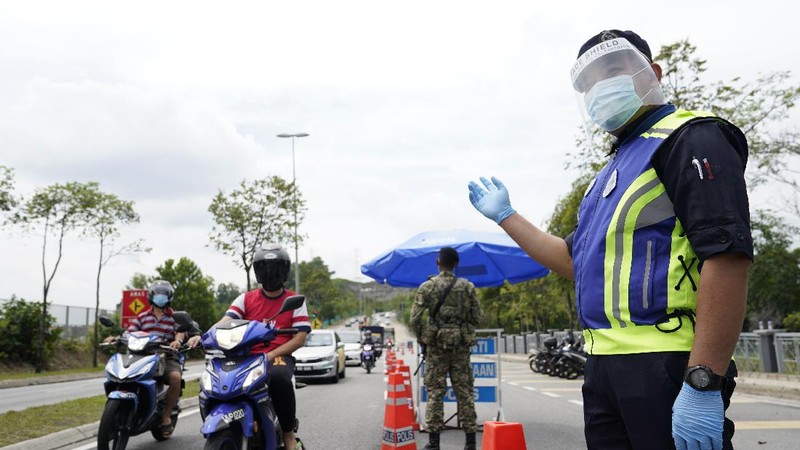 Police officers check vehicles at roadblock to ensure that people abide by the movement control order on the outskirts of Kuala Lumpur, Malaysia, Wednesday, Oct. 14, 2020. Malaysia will restrict movements in its biggest city Kuala Lumpur, neighboring Selangor state and the administrative capital of Putrajaya from Wednesday to curb a sharp rise in coronavirus cases. (AP Photo/Vincent Thian)