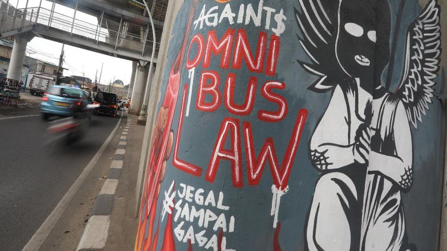 Warga melintas di depan mural penolakan terhadap pengesahan RUU Cipta Kerja atau Omnibus Law oleh DPR di kawasan Pesanggrahan, Jakarta Selatan, Rabu (13/10/2020). Mural tersebut dibuat setelah unjuk rasa menolak disahkannya RUU Cipta Kerja. (CNBC Indonesia/Andrean Kristianto)