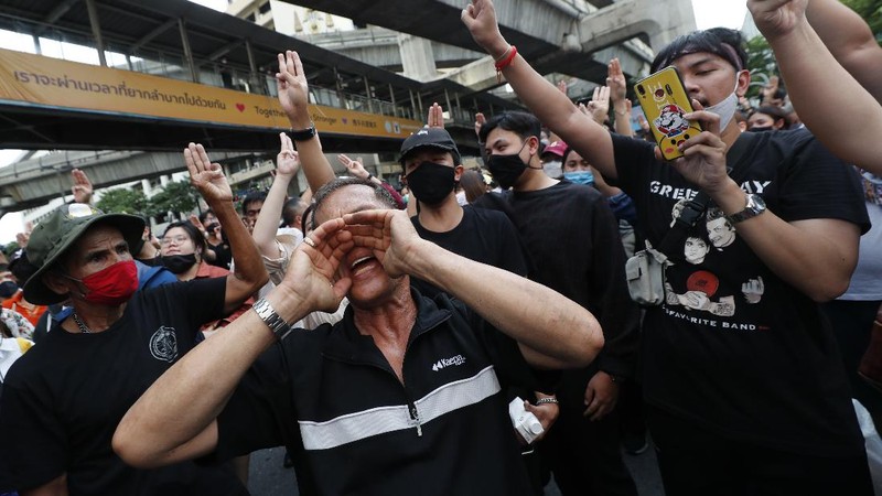 Pro-democracy protesters flash three-fingered salute during a protest as they occupied a main road at the central business district in Bangkok, Thailand, Thursday, Oct. 15, 2020. Thailand's government declared a strict new state of emergency for the capital on Thursday, a day after a student-led protest against the country's traditional establishment saw an extraordinary moment in which demonstrators heckled a royal motorcade. (AP Photo/Gemunu Amarasinghe)