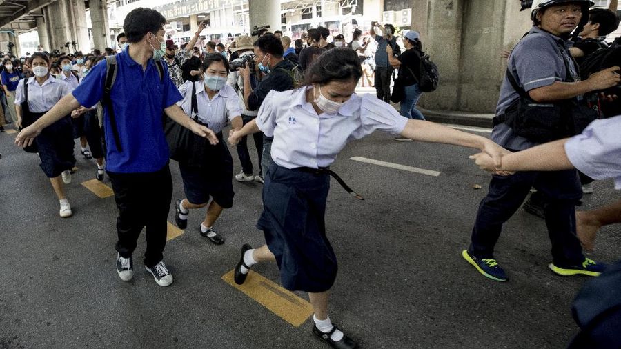 Pro-democracy protesters flash three-fingered salute during a protest as they occupied a main road at the central business district in Bangkok, Thailand, Thursday, Oct. 15, 2020. Thailand's government declared a strict new state of emergency for the capital on Thursday, a day after a student-led protest against the country's traditional establishment saw an extraordinary moment in which demonstrators heckled a royal motorcade. (AP Photo/Gemunu Amarasinghe)