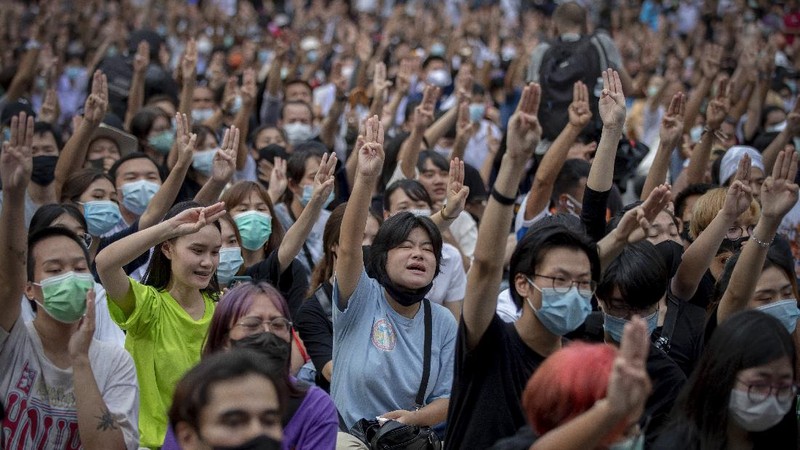 Pro-democracy protesters flash three-fingered salute during a protest as they occupied a main road at the central business district in Bangkok, Thailand, Thursday, Oct. 15, 2020. Thailand's government declared a strict new state of emergency for the capital on Thursday, a day after a student-led protest against the country's traditional establishment saw an extraordinary moment in which demonstrators heckled a royal motorcade. (AP Photo/Gemunu Amarasinghe)
