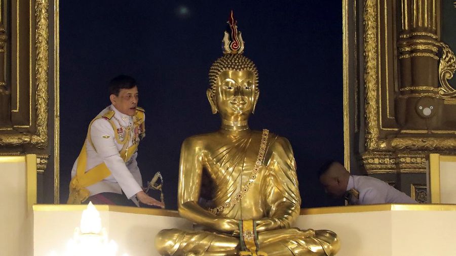 Thailand's King Maha Vajiralongkorn stands beside a giant Buddhist statue as he presides over religious rites at the annual royal Kathin ceremony at Wat Ratchabophit temple in Bangkok, Thailand, Saturday, Oct. 10, 2020. Kathin is a Buddhist religious ceremony at which robes are donated to monks at their temples,often along with living essentials such as cooking utensils and toiletries. It is a way for Buddhist laypeople to show their religious devotion. (Manager Online via AP)