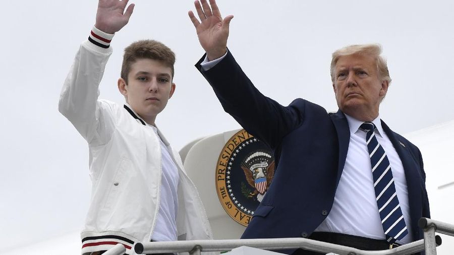 FILE - In this Aug. 16, 2020 file photo, President Donald Trump, right, and his son Barron Trump wave from the top of the steps to Air Force One at Morristown Municipal Airport in Morristown, N.J.  (AP Photo/Susan Walsh)