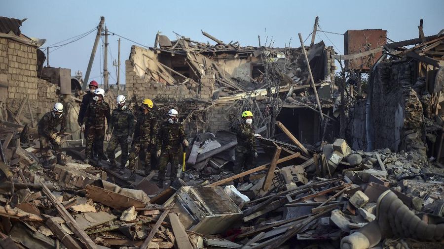 Soldiers and firefighters search for survivors in a residential area that was hit by rocket fire overnight by Armenian forces, early Saturday, Oct. 17, 2020, in Gyanga, Azerbaijan's second largest city, near the border with Armenia. (AP Photo/Aziz Karimov)