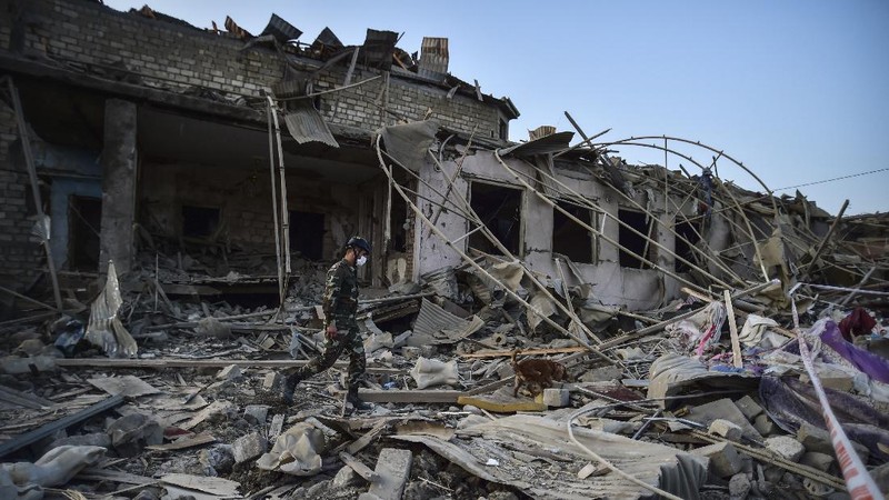 Soldiers and firefighters search for survivors in a residential area that was hit by rocket fire overnight by Armenian forces, early Saturday, Oct. 17, 2020, in Gyanga, Azerbaijan's second largest city, near the border with Armenia. (AP Photo/Aziz Karimov)