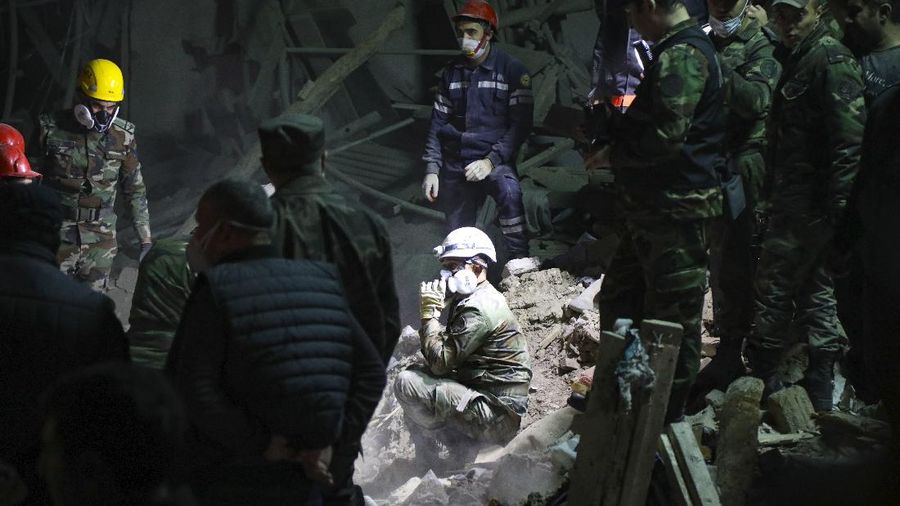 Soldiers and firefighters search for survivors in a residential area that was hit by rocket fire overnight by Armenian forces, early Saturday, Oct. 17, 2020, in Gyanga, Azerbaijan's second largest city, near the border with Armenia. (AP Photo/Aziz Karimov)